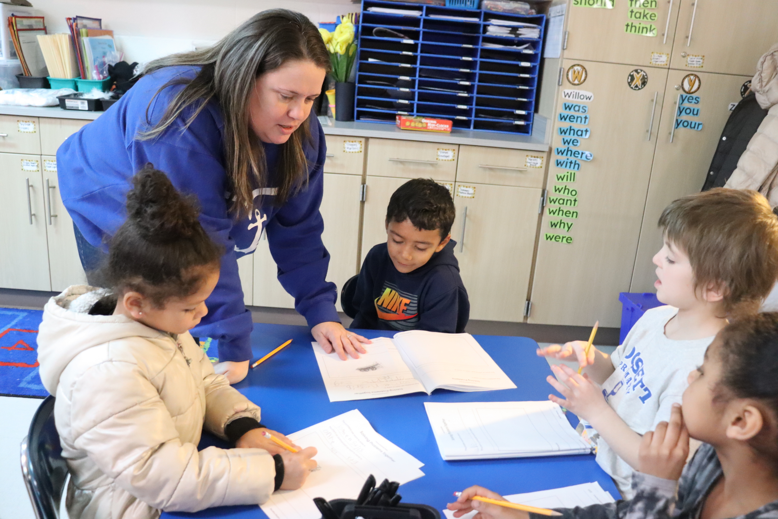Teacher helping students with journals.